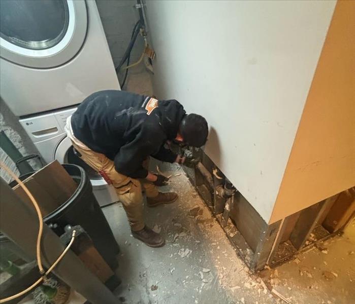 SERVPRO technician inspecting basement laundry room flood cuts