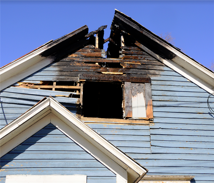 a fire damaged house with a burnt roof